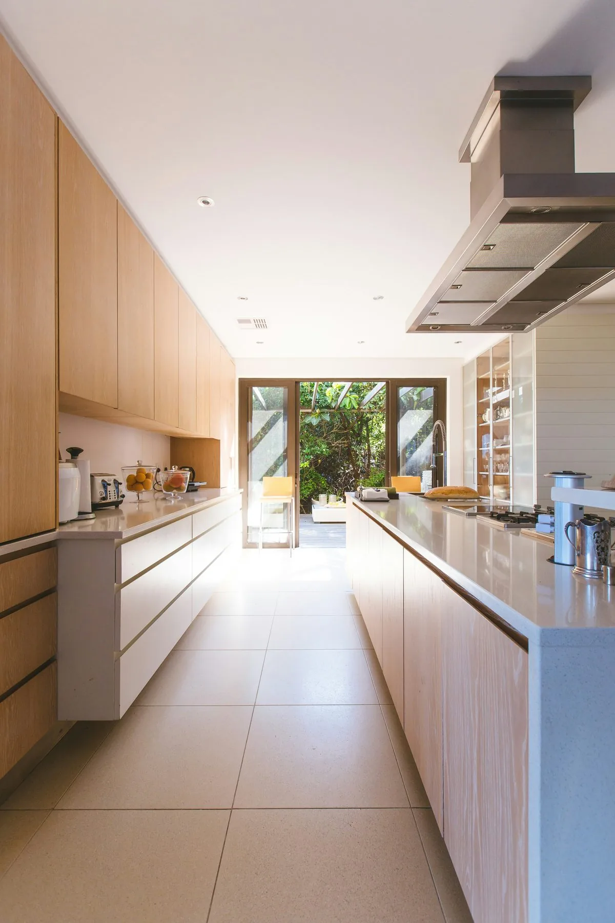 Cocina en línea con carpintería de madera clara y salida directa al jardín